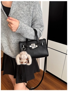 Detail of black pebbled leather handbag with silver lock and brown rabbit charm