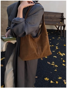 Close-up of large dark brown suede tote bag with contrast stitching and autumn street vibes