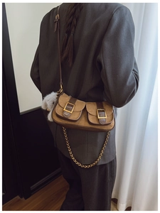 Detail of suede crossbody bag with metal chain, pockets and plush puppy charm