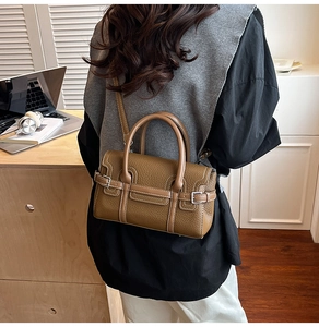 Detail of caramel lychee grain leather handbag with silver buckles on a desktop