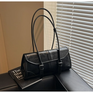 Macro detail of black oil-wax leather baguette bag with metal buckle straps and soft shadows