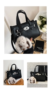 Detailed view of black litchi grain tote bag with silver lock and plush bunny charm