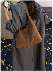 Detail of a large brown hobo tote bag with white contrast stitching on a grey winter coat