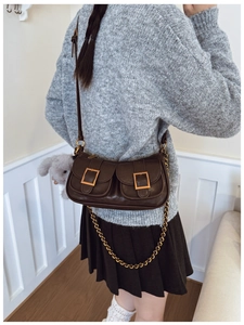 Detail of vintage brown dumpling bag with gold buckle pockets and a plush bunny charm