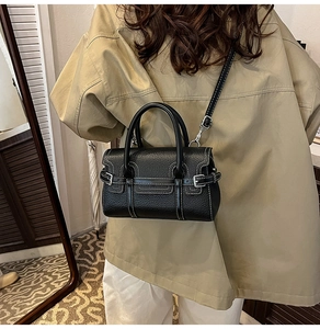 Detail of black pebbled leather handbag with white contrast stitching and shoulder strap