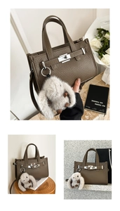 Detail of dark brown leather handbag with litchi texture and cute plush bunny charm