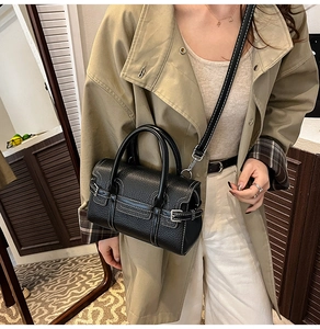 Detailed view of black lychee leather handbag with white contrast stitching and double handles