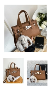 Detail of brown litchi pattern leather handbag with silver lock and plush bunny charm