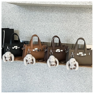 Detailed view of four textured litchi leather handbags with metal turn-lock and bunny charm