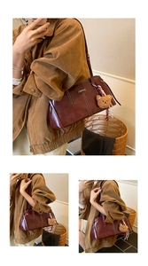 Detail showing burgundy leather shoulder bag with white stitching and plush bear charm