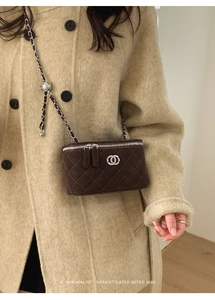 Close-up of quilted dark brown matte vanity bag with silver chain strap and metal logo