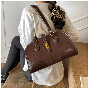 Detail der braunen Wildleder-Boston-Tasche mit Lederbesatz und goldenem Drehverschluss