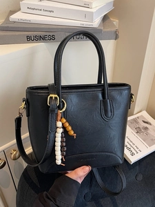 Chic black lychee texture bucket bag with beaded charm and adjustable strap