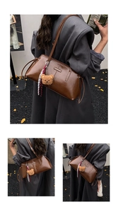 Detail of a brown glossy leather shoulder bag with plush bear pendant and ribbon detail