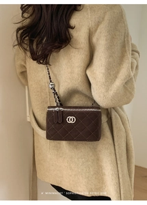 Detail of dark brown quilted box bag with silver chain strap and metal adjustment ball