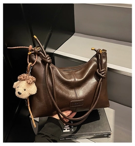 Detailed view of deep brown vintage shoulder bag featuring a unique knotted handle and bear charm