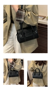 Close-up of black pebble leather handbag featuring white contrast stitching and silver hardware