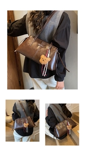 Detail view of vintage brown leather shoulder bag with plush bear charm and fashion logo