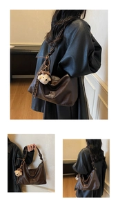 Detailed view of dark brown leather hobo bag with teddy charm and knotted handle strap