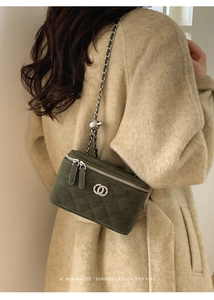 Detail of dark green quilted suede box bag with silver chain strap on model coat