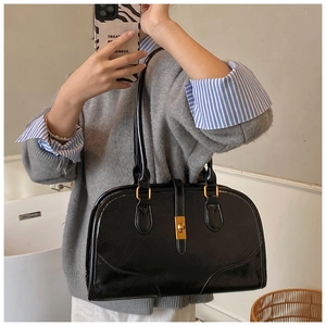 Detailansicht der schwarzen glänzenden Ledertasche mit goldener Metallschnalle und Schloss