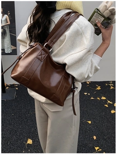 Seitenansicht einer dunkelbraunen Bowling-Tasche aus Glanzleder mit breitem Riemen