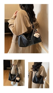 Detail of black soft leather underarm bag featuring shoulder knot and plush bear charm