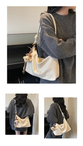 Detail of cream-white tote bag featuring soft leather texture and plush bear pendant