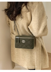Deep green quilted box bag with chain strap styled on a minimalist wool coat
