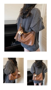 Detail of vintage brown leather hobo bag with teddy bear pendant and tassel decor