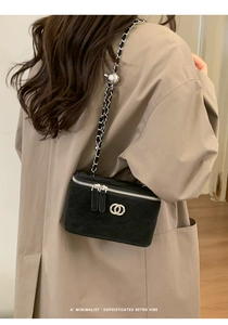 Detail of black quilted mini box bag with silver chain strap and adjustable metal ball