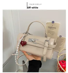 Détail du sac à main rectangulaire blanc crème avec fermoir argenté et breloque