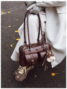 Détail du sac à bandoulière en cuir ciré marron foncé avec breloque ours en peluche et poches