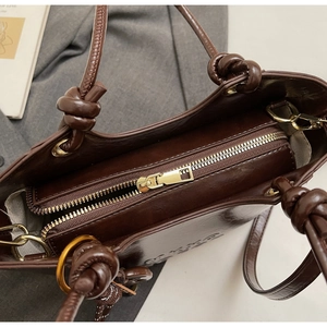 Detailed top view of dark brown leather tote bag with zip closure and knotted handles