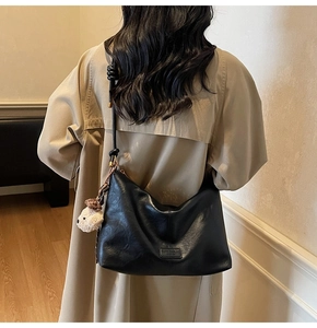 Detail of black faux leather shoulder bag with plush bear charm and leopard bow