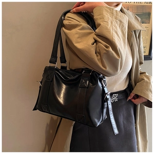 Detail der schwarzen Tote-Bag aus Kunstleder mit breitem Griff in einem Fashion-Shooting