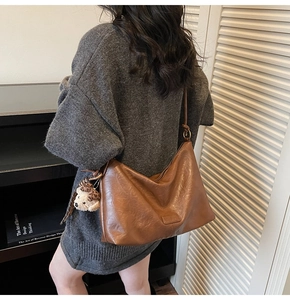 Detail view of brown vintage hobo bag with teddy bear charm and fine stitching details