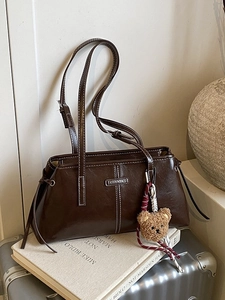 Retro chocolate faux leather handbag with contrast stitching and bear charm on suitcase