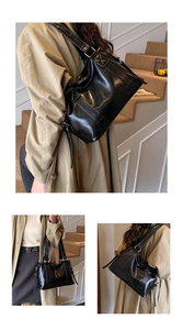 Detail einer großen schwarzen glänzenden Leder-Achseltasche mit breiten Riemen und Design