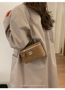 Brown quilted chain bag with silver buckle worn over the shoulder in a minimalist retro style
