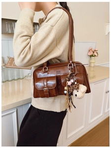 Détail d'un sac à bandoulière en similicuir marron avec poches et breloque chiot en peluche