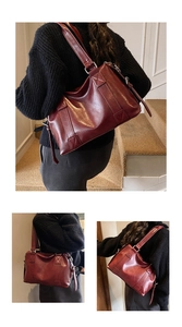 Detail einer dunkelroten Vintage-Boston-Tasche mit breitem Schultergurt und Banddesign