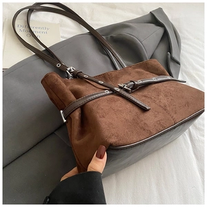 Détail d'un sac cabas marron mat avec œillets métalliques sur un costume gris élégant