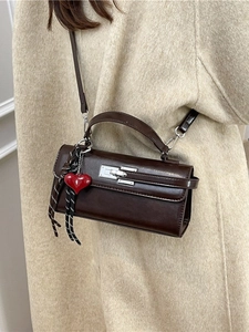 Sac à main rectangulaire marron foncé avec boucle argentée et breloque cœur sur manteau