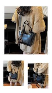 Détails du sac seau en cuir noir avec logo embossé et bandoulière réglable pratique