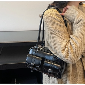 Detail of black vintage underarm bag with double front pockets and metallic buckles