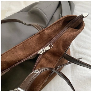 Détail de la fermeture éclair métallique et des anses en cuir du sac cabas marron