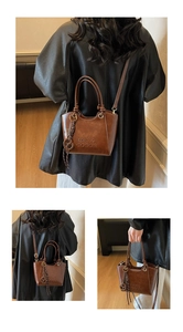 Détail du sac seau marron rétro montrant le logo gaufré et le pendentif rond en métal