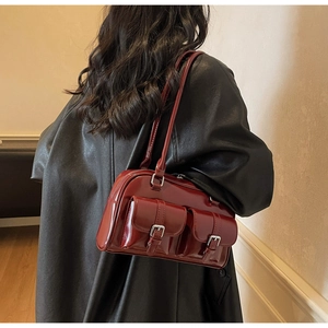 Detail of wine red glossy shoulder bag with double pockets and silver buckles
