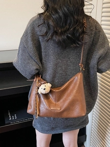 Brown vintage faux leather tote bag with bear keychain shown on casual grey sweater